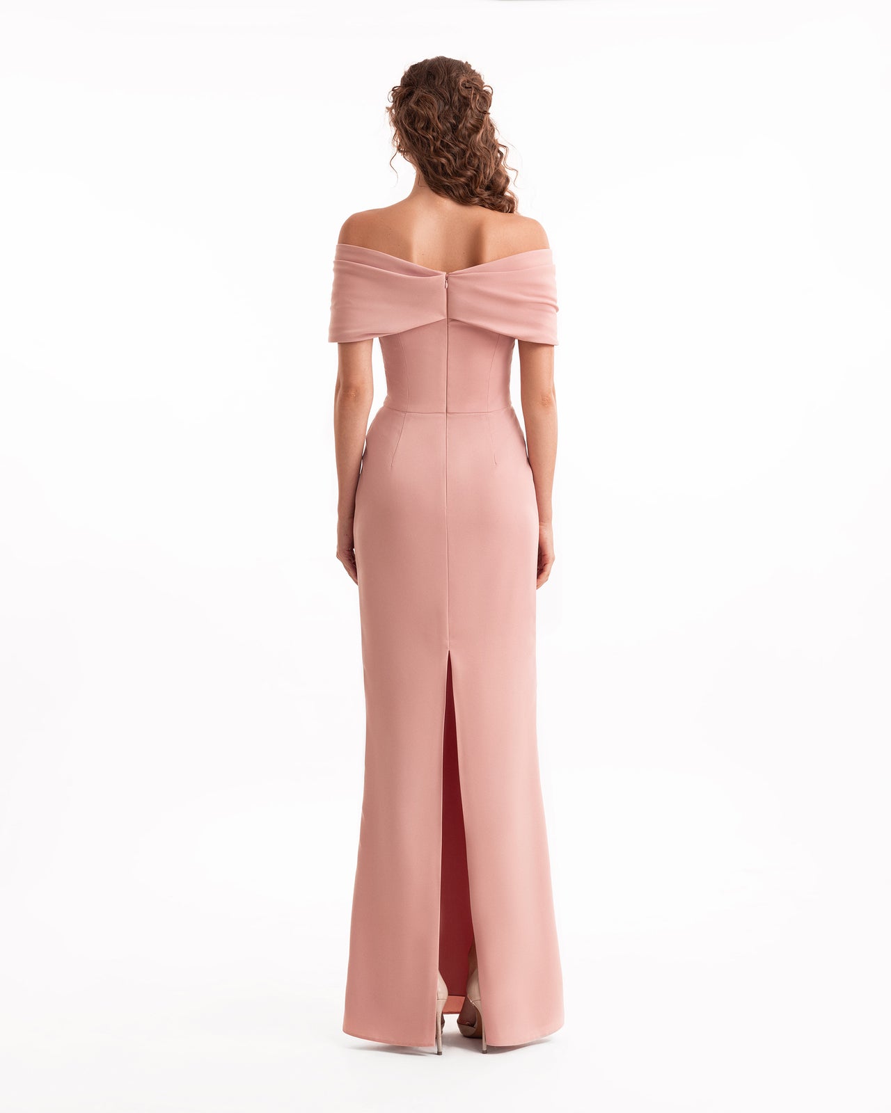 Woman wearing a pink off-shoulder gown with a slit on a white background