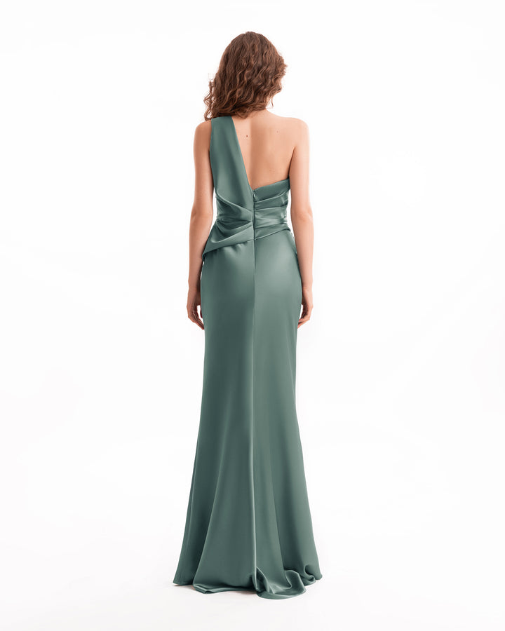 Woman wearing a green one-shoulder evening gown on a white background