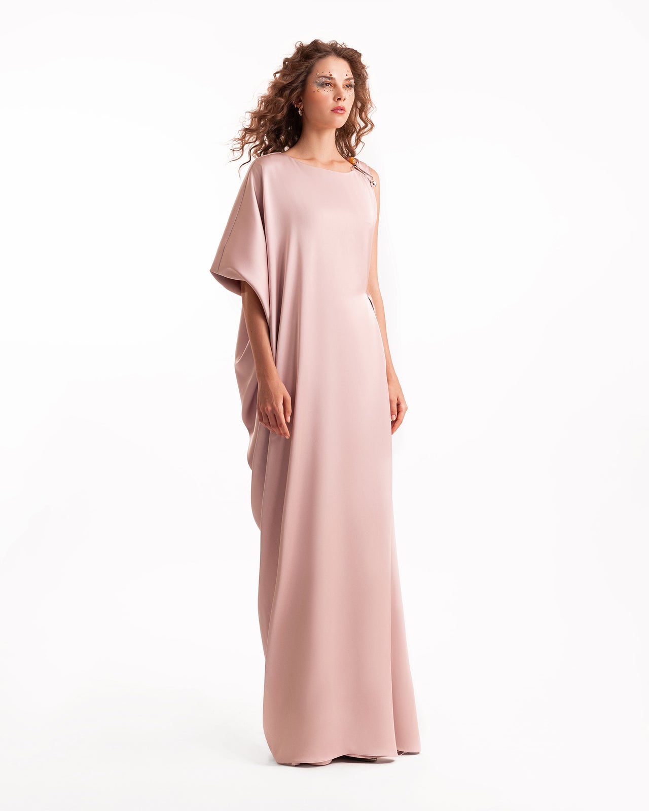 Woman wearing a long, light pink dress on a white background