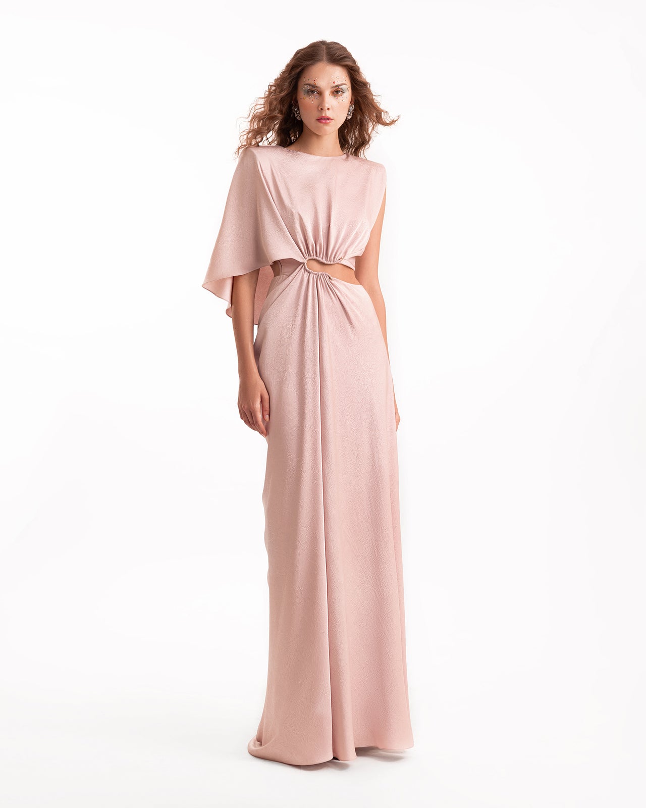 Woman wearing a long, light pink dress with a belt on a white background