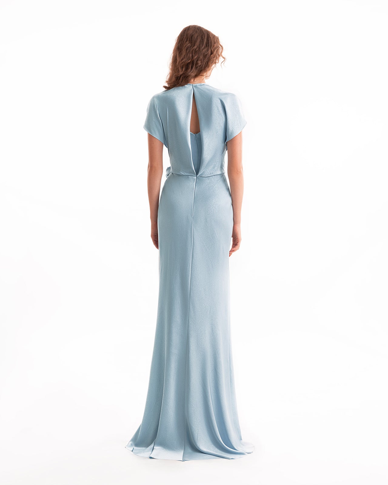 Woman wearing a light blue evening gown with a slit back on a white background
