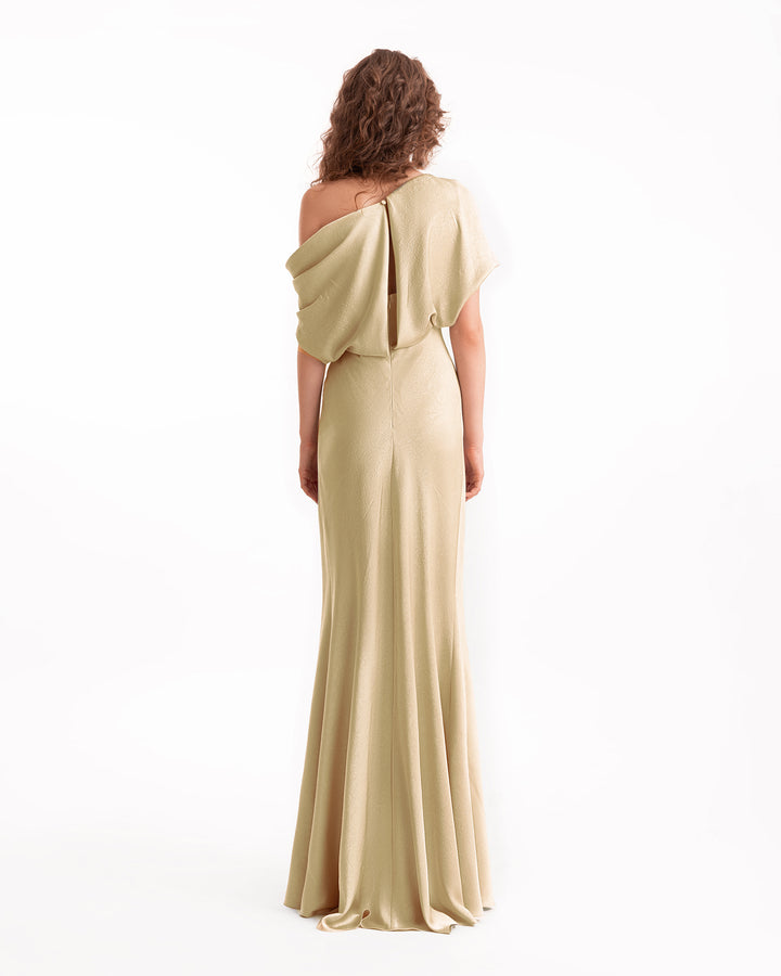 Woman wearing a beige one-shoulder evening gown on a white background