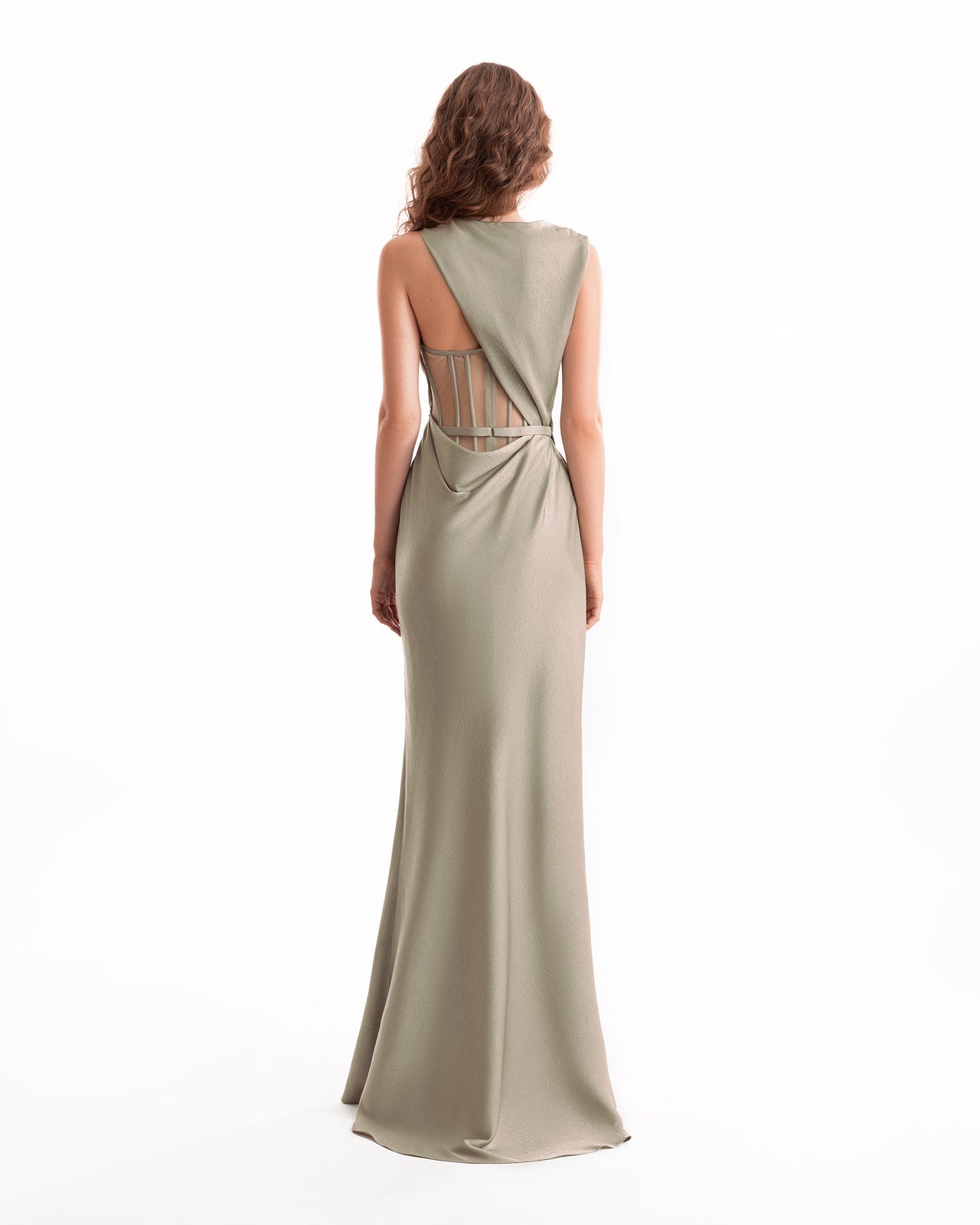 Woman wearing a long, one-shoulder dress with cut-out back on a white background