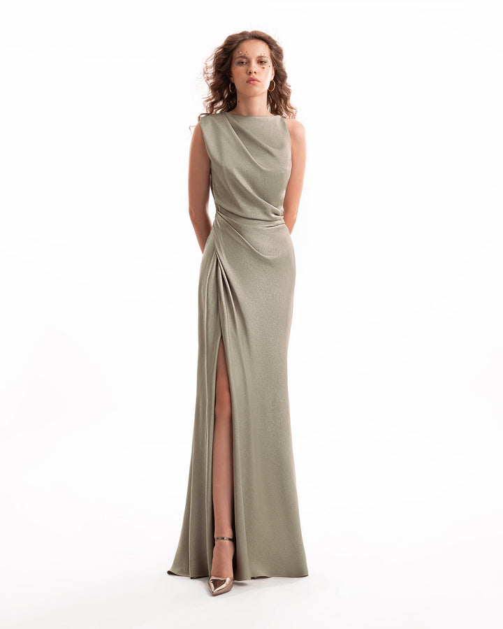 Woman wearing a long, sleeveless olive green dress with a slit on a white background