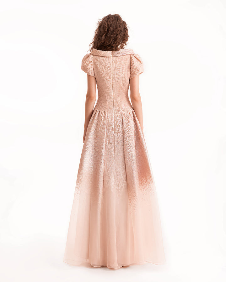 Woman wearing a long, light pink dress on a white background