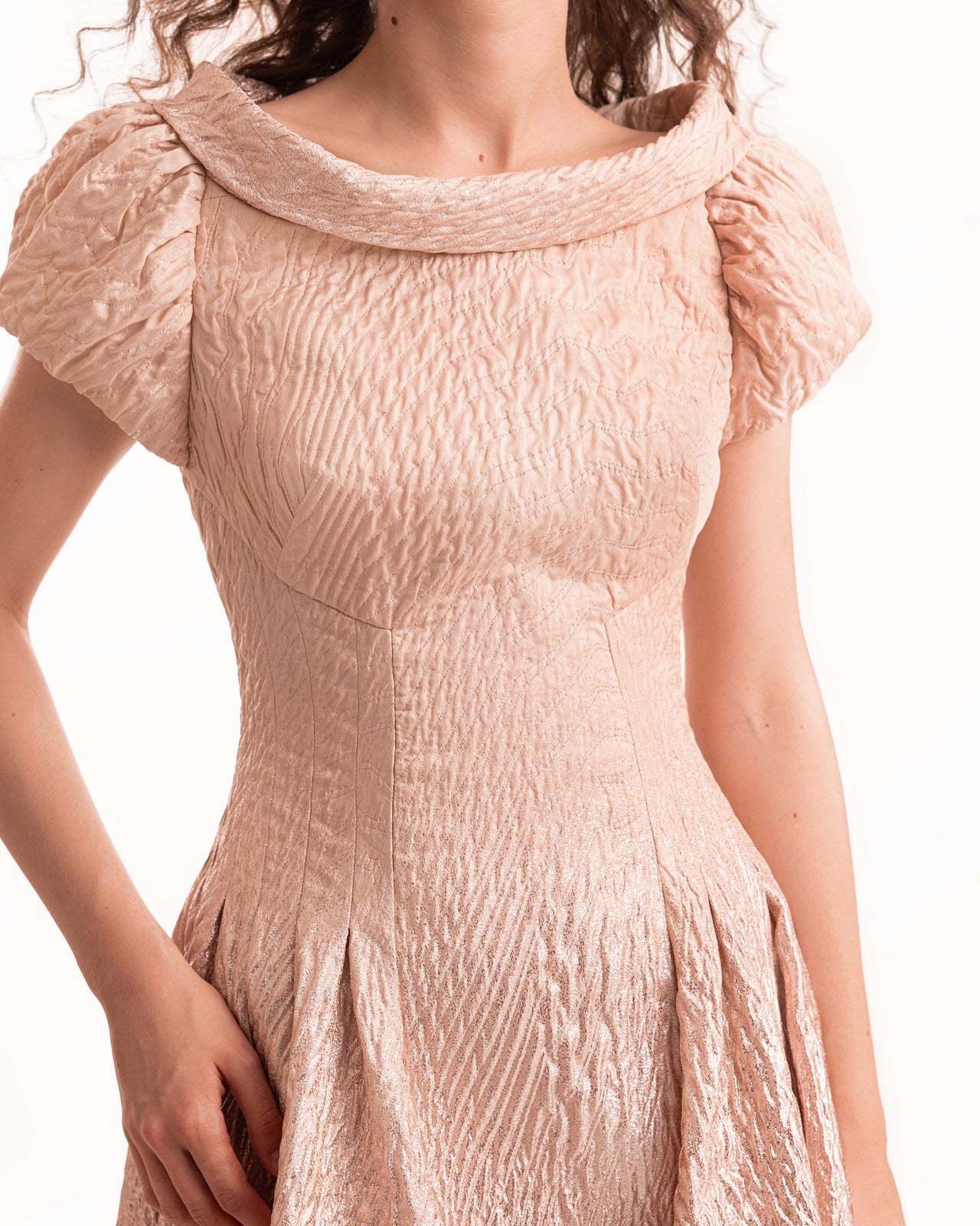 Close-up of a textured pink dress with ruffled shoulders on a white background