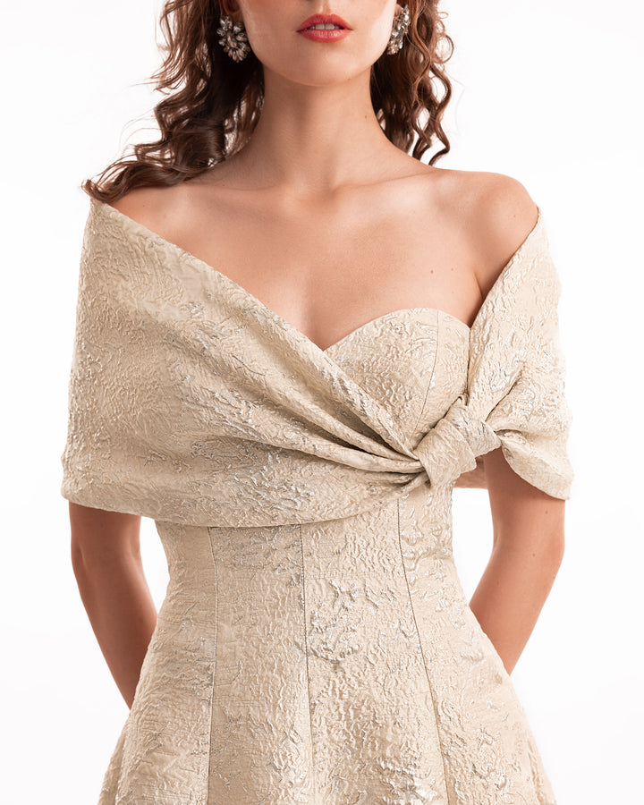 Beige off-shoulder dress with intricate detailing on a white background