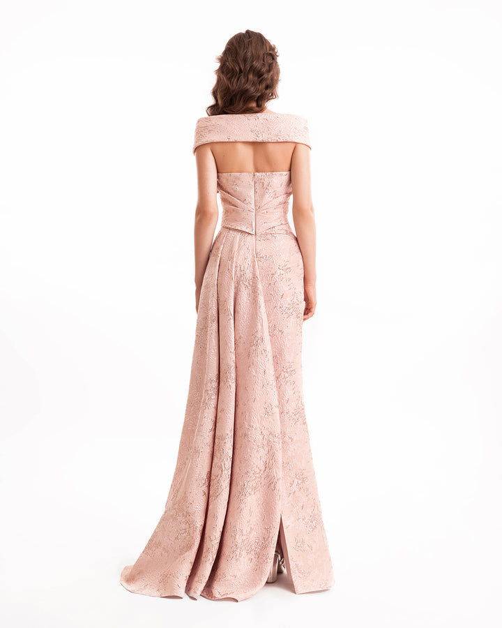 Woman wearing a long, off-shoulder pink dress with lace details on a white background