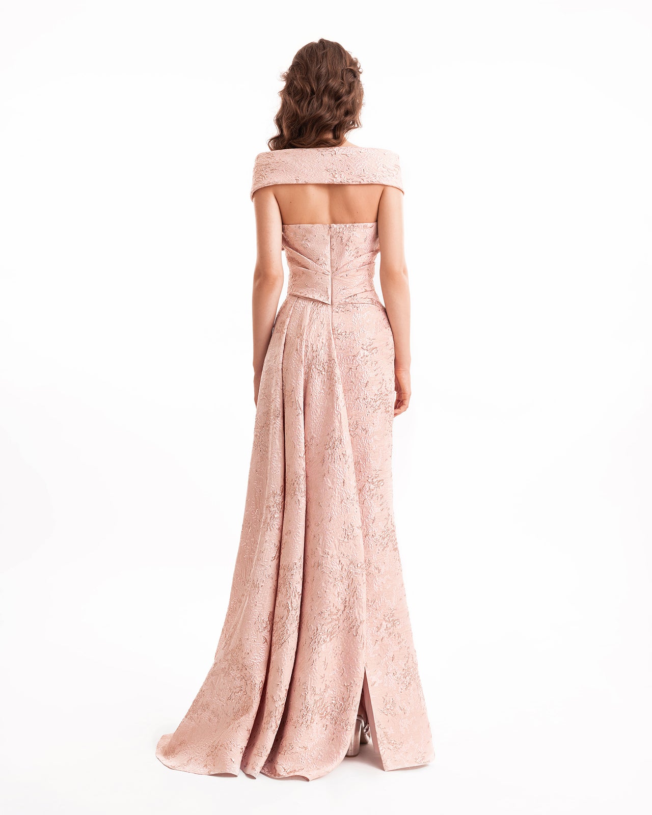 Woman wearing a long, off-shoulder pink dress with lace details on a white background