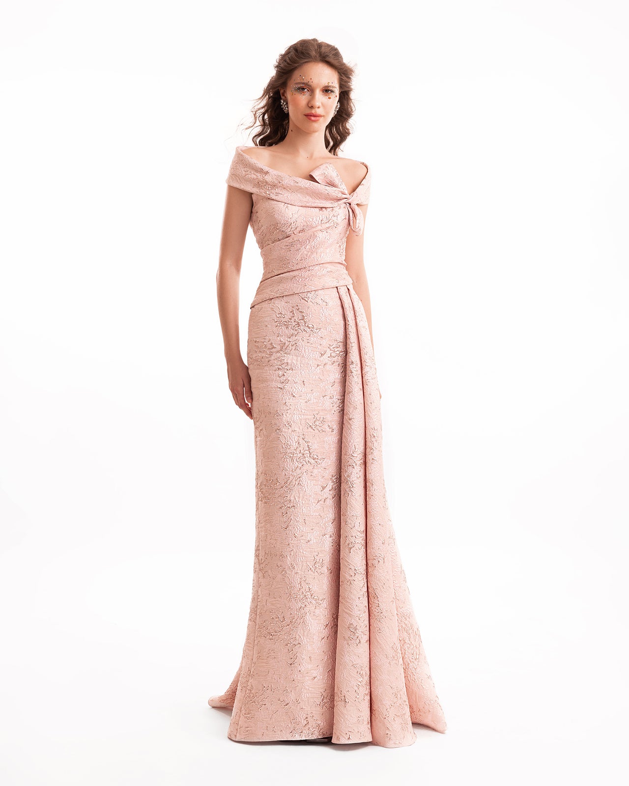 Woman wearing a pink off-shoulder evening gown on a white background