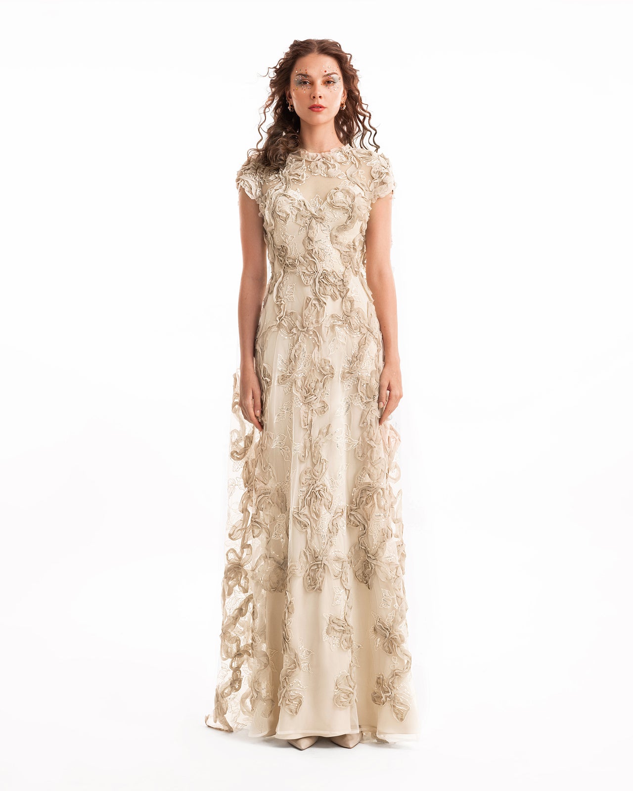 Woman wearing a long, floral lace dress on a white background