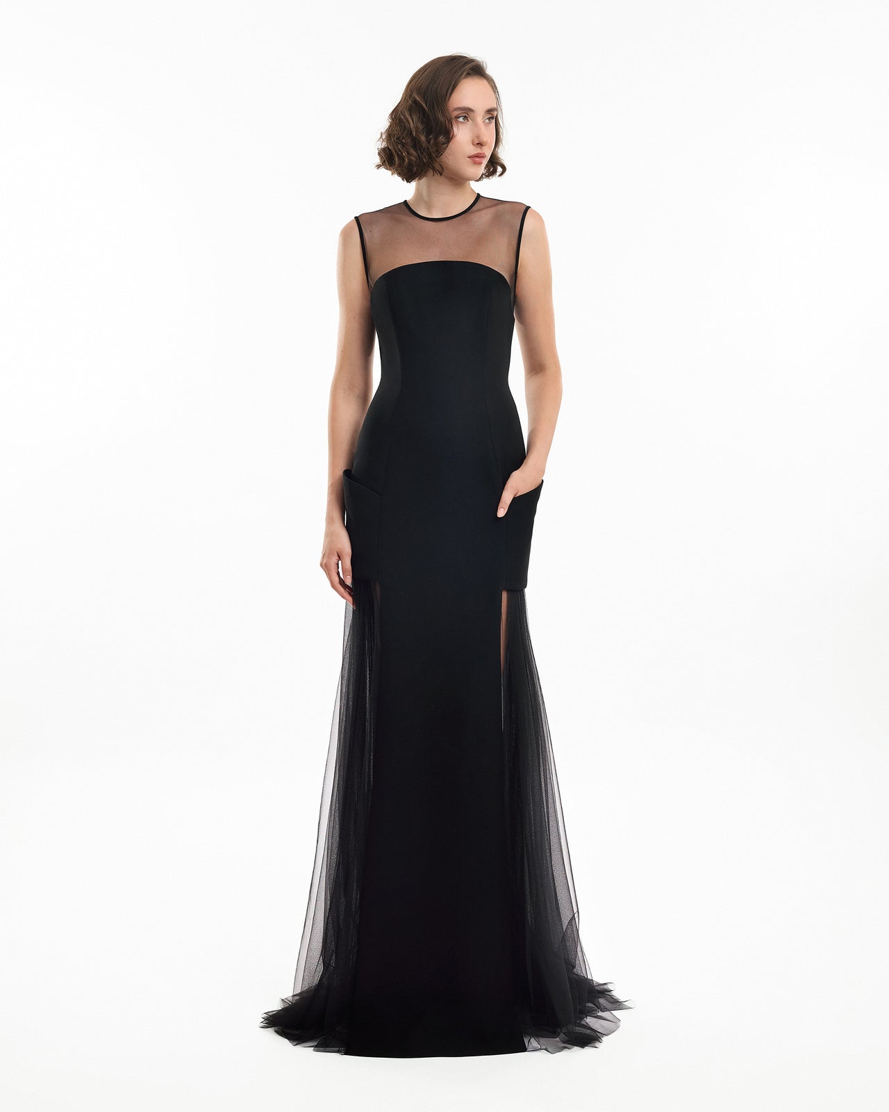 Woman wearing a black evening gown with sheer overlay on a white background