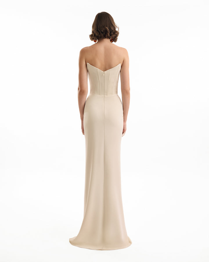 Woman wearing a strapless beige evening gown on a white background