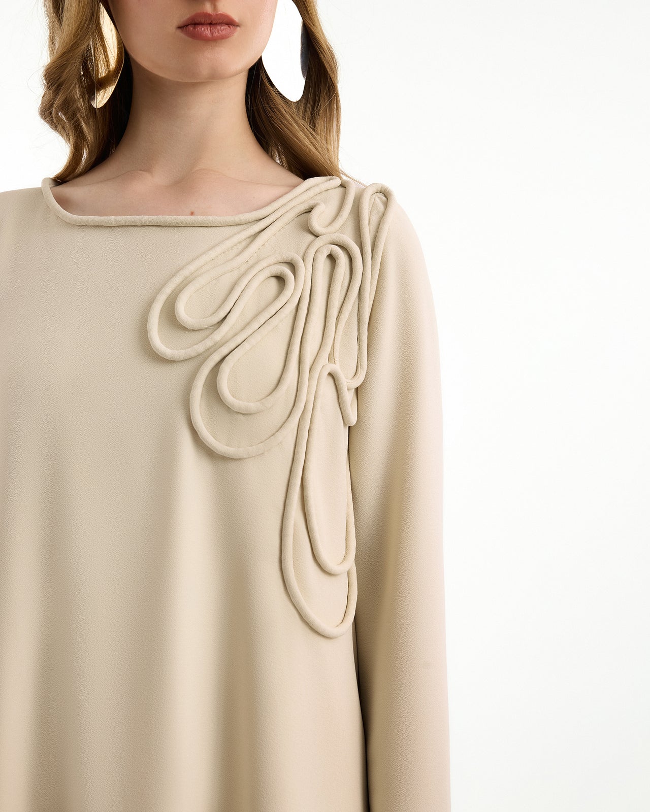 Beige dress with decorative shoulder detail on a white background