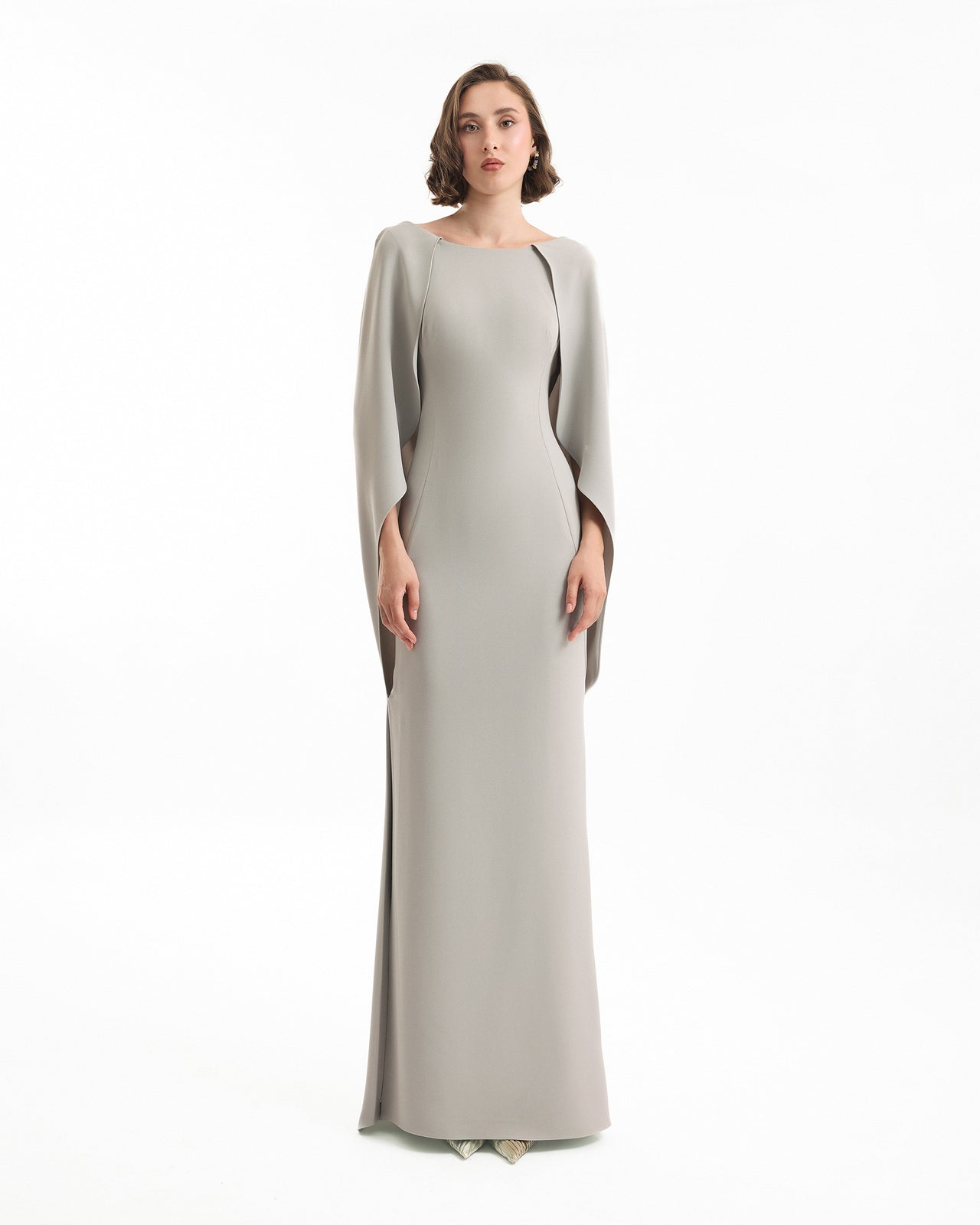 Woman wearing a long, light gray dress on a white background