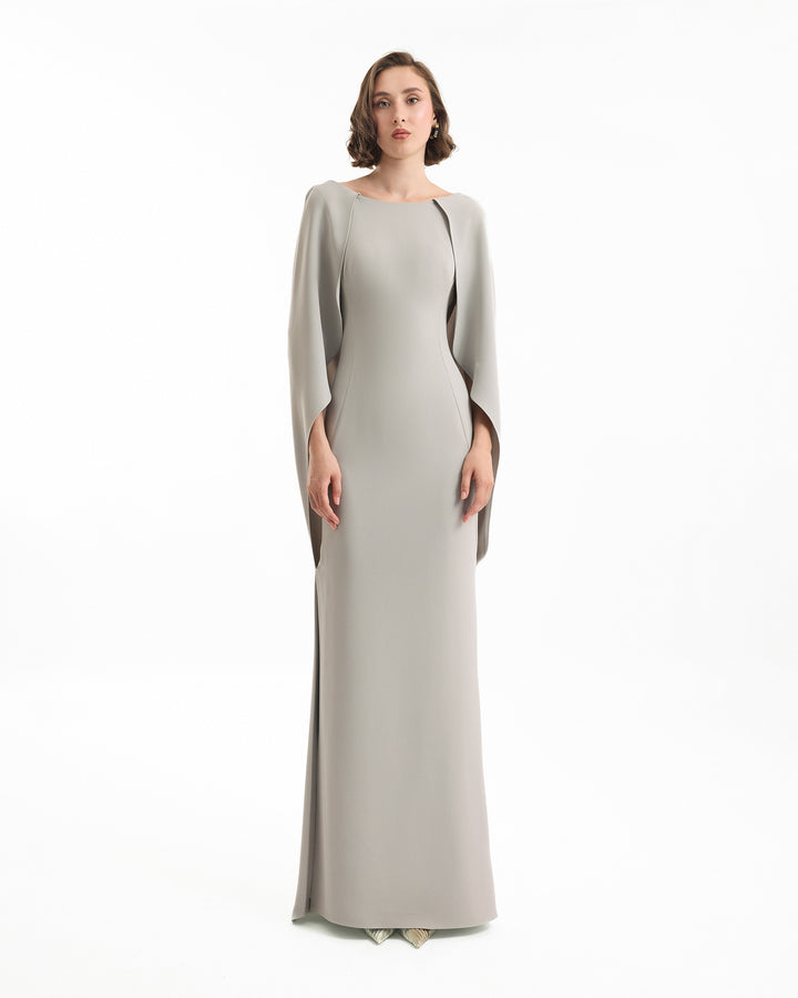 Woman wearing a long, light gray dress on a white background