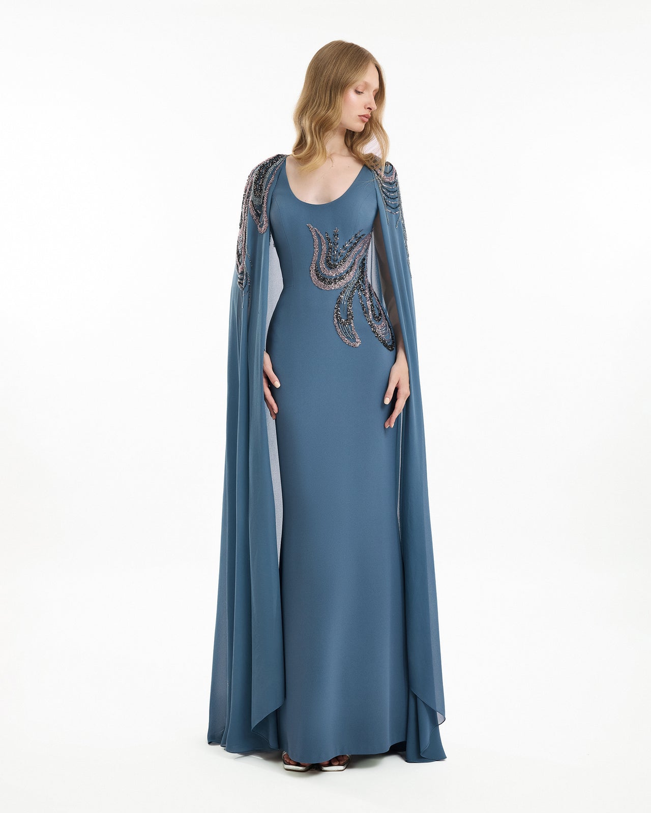 Woman wearing a blue evening gown with a cape on a white background