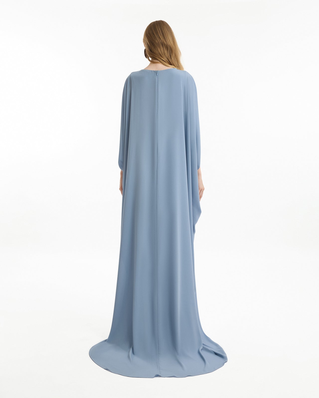 Woman wearing a long, light blue dress with a cape on a white background