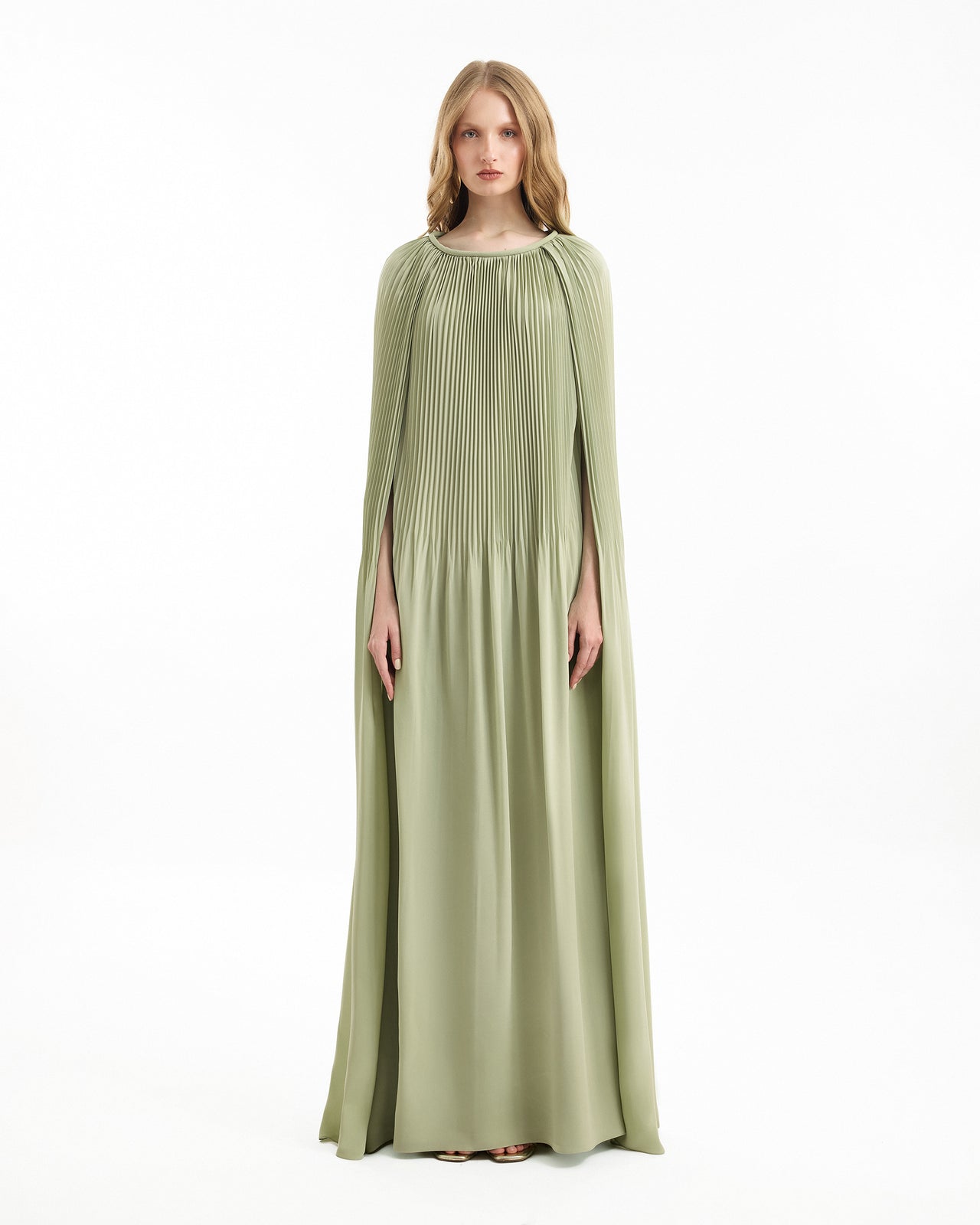 Woman wearing a long green dress with cape on a white background
