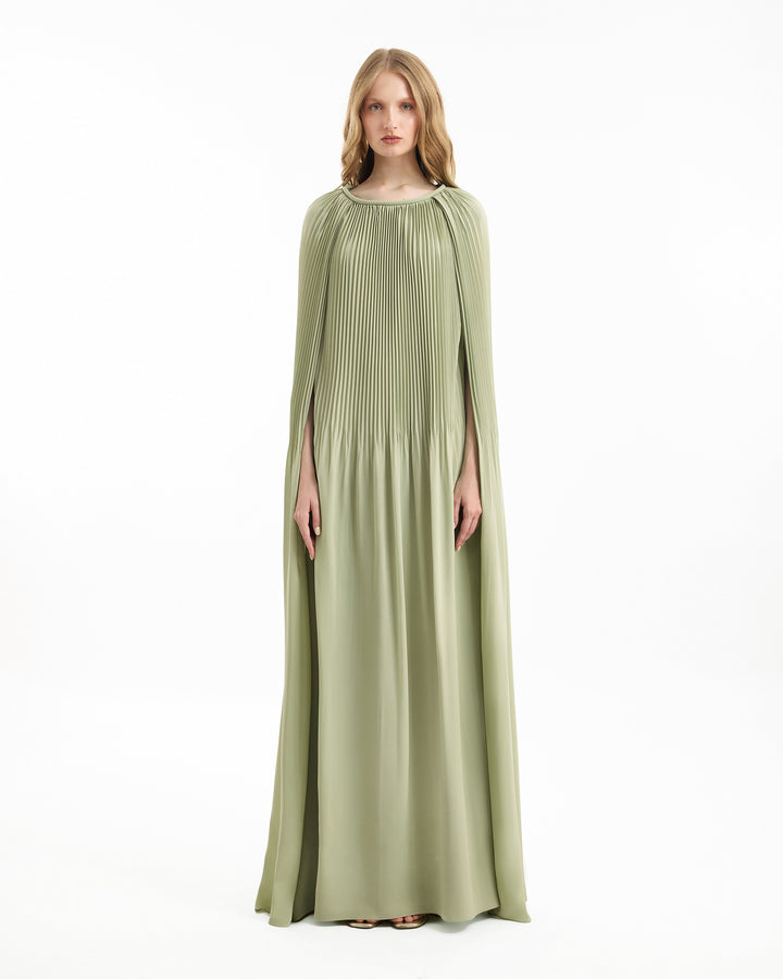 Woman wearing a long green dress with cape on a white background