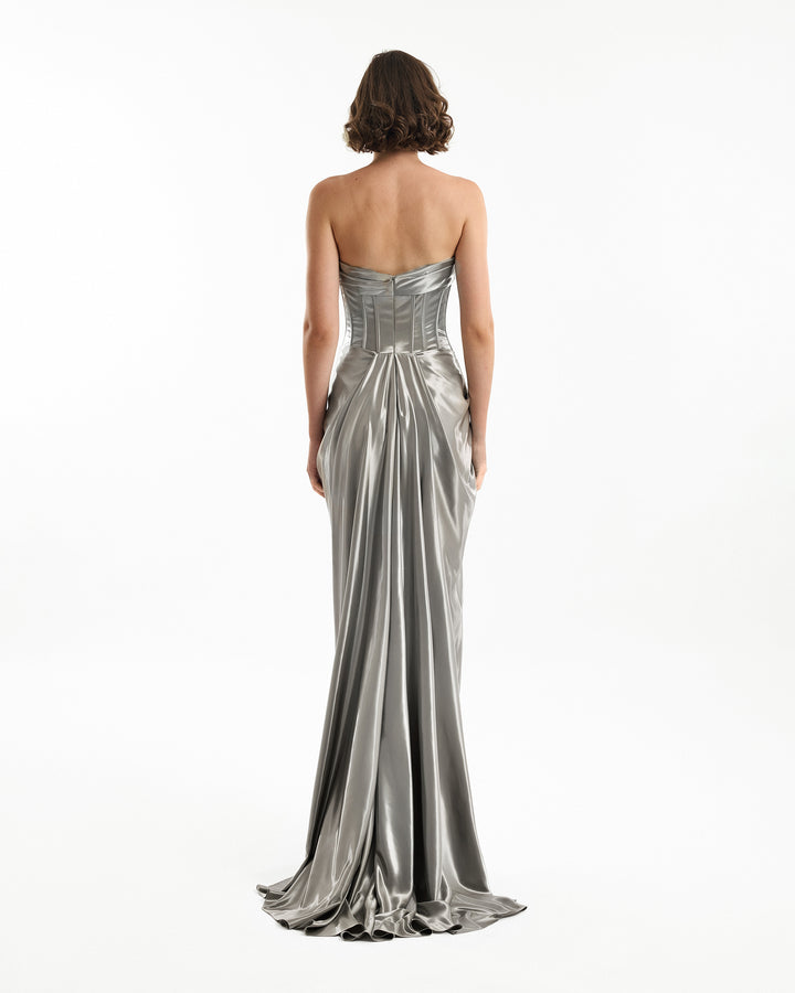 Woman wearing a silver strapless gown on a white background