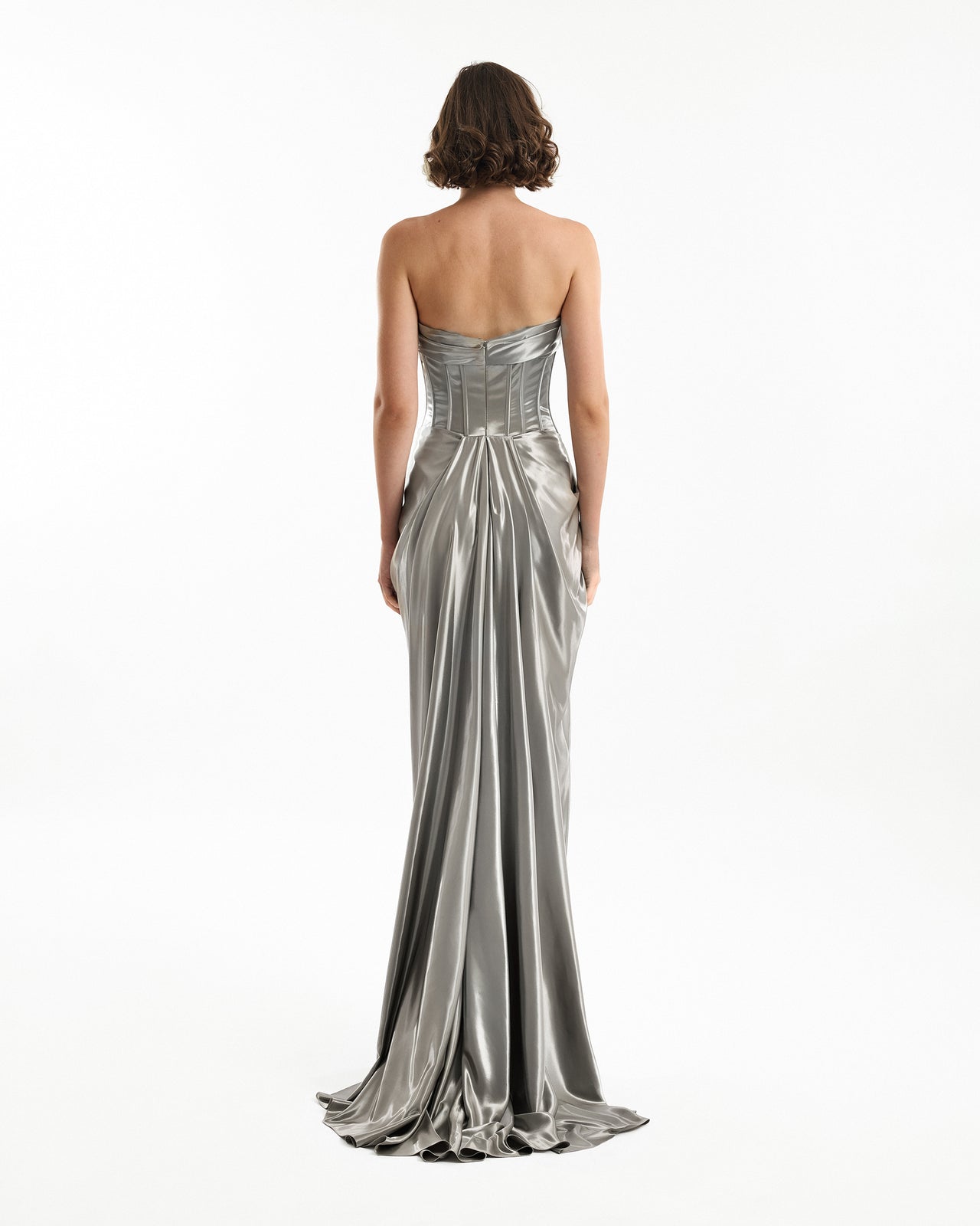 Woman wearing a silver strapless gown on a white background