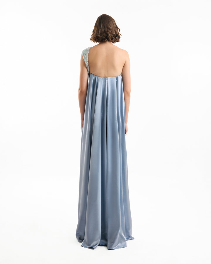 Woman wearing a light blue one-shoulder gown on a white background