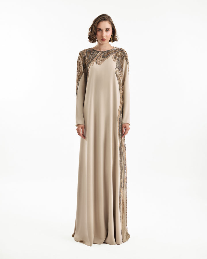 Woman wearing a long, elegant dress with intricate detailing on a white background