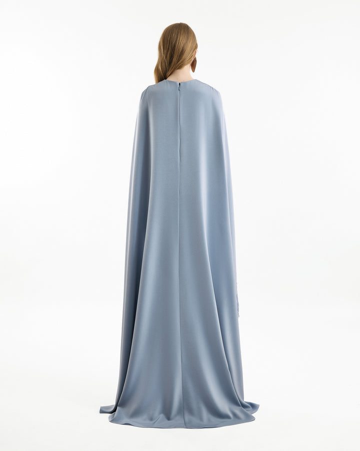 Person wearing a long, light blue cape on a white background