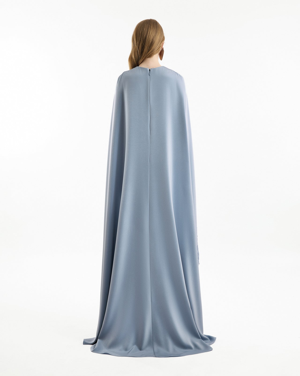 Person wearing a long, light blue cape on a white background