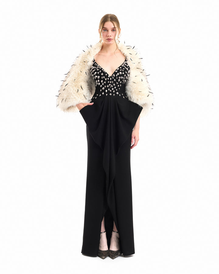 A model wearing a long black evening gown with a beaded bodice and a voluminous white feathered bolero, photographed against a solid white background.