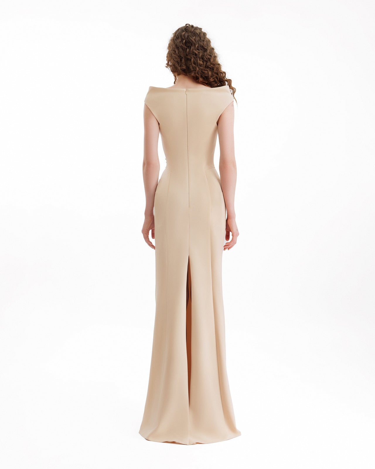 Woman wearing a beige evening gown with a slit on a white background