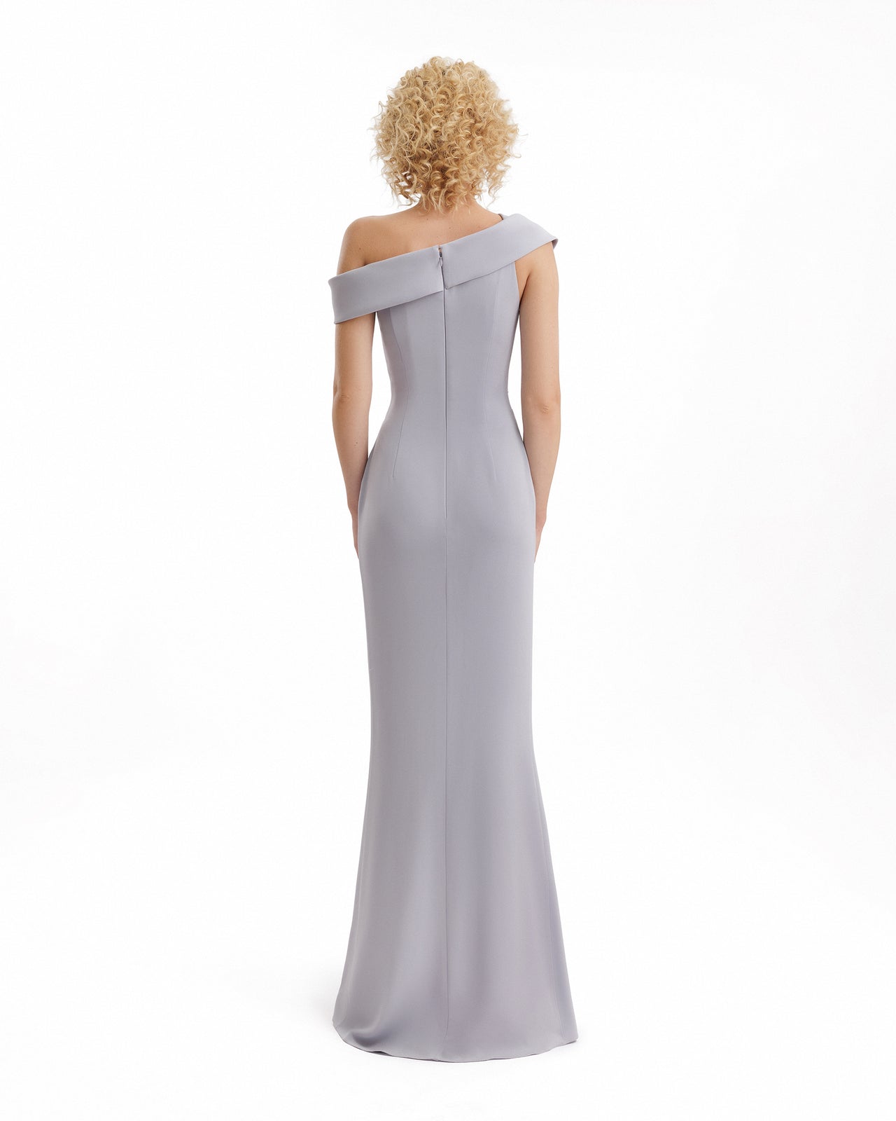 Woman wearing a one-shoulder gray gown on a white background