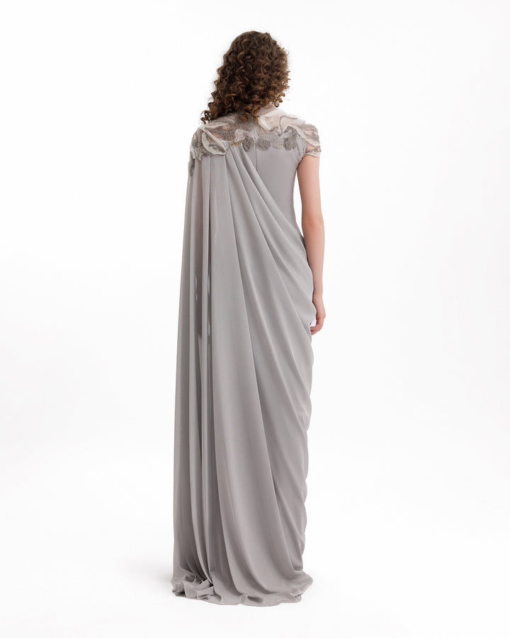 Woman wearing a long, elegant gray dress with lace details on a white background