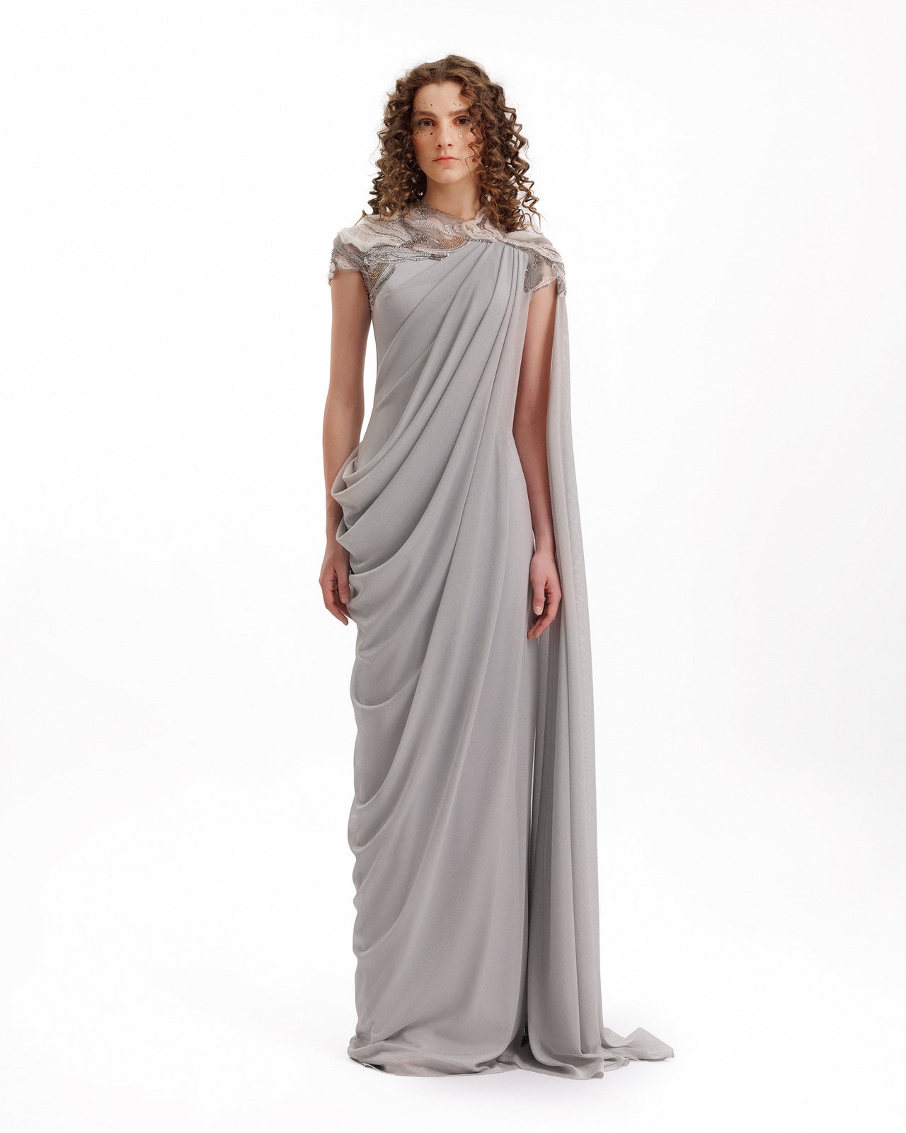Woman wearing a gray draped gown on a white background