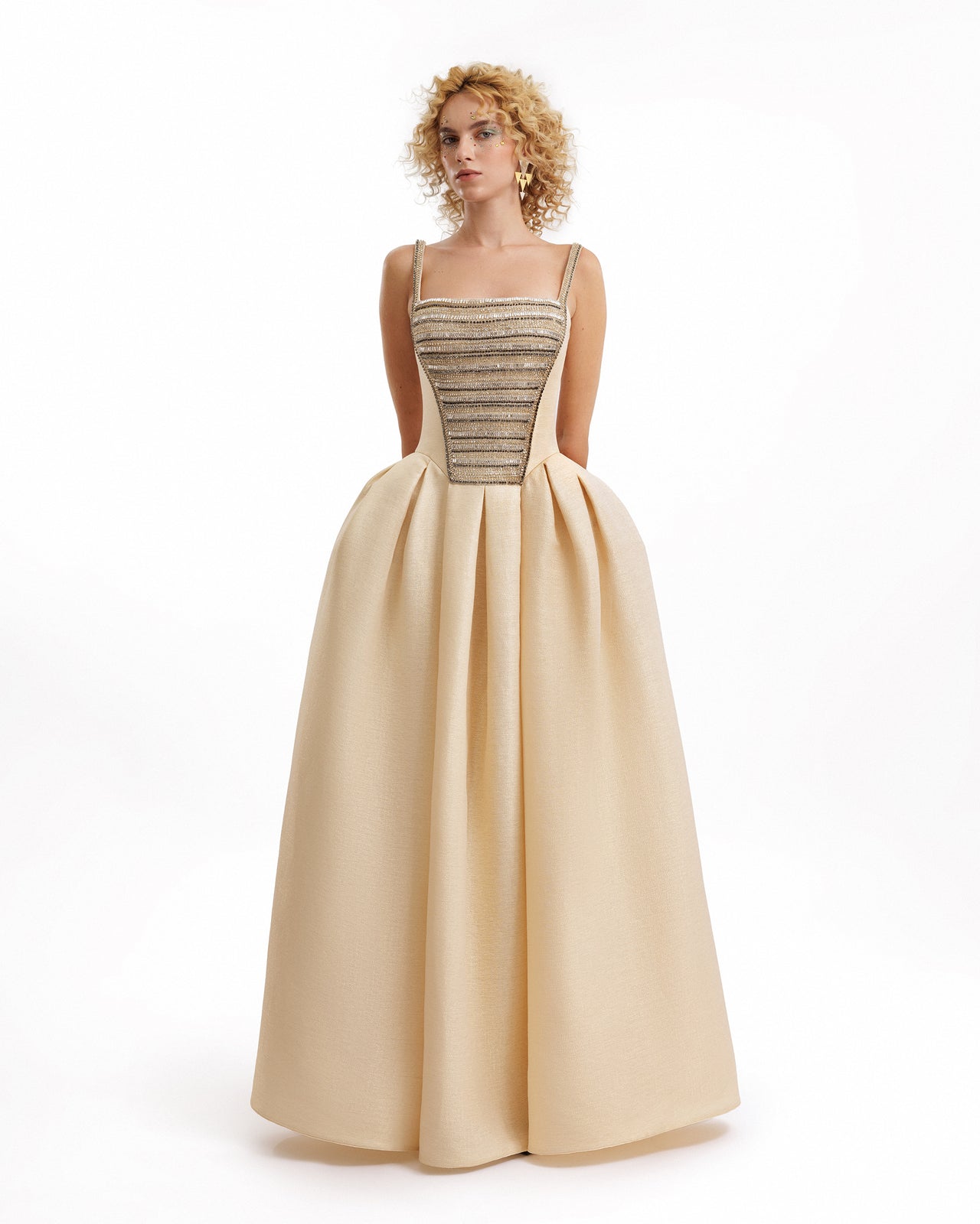 Woman wearing a gold evening gown with a white background