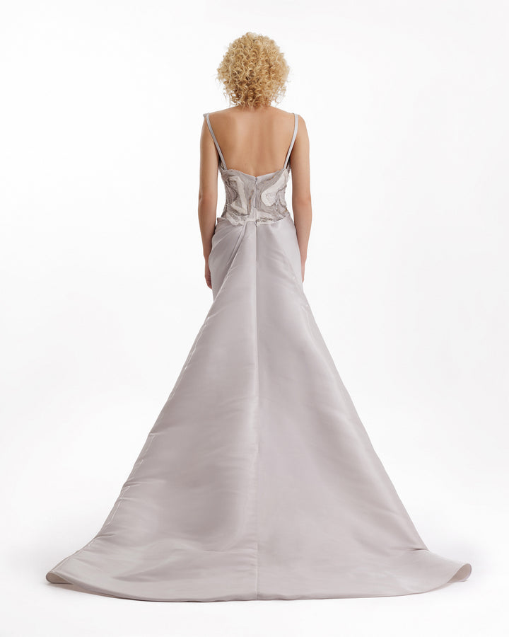 Woman wearing a silver evening gown with a white background