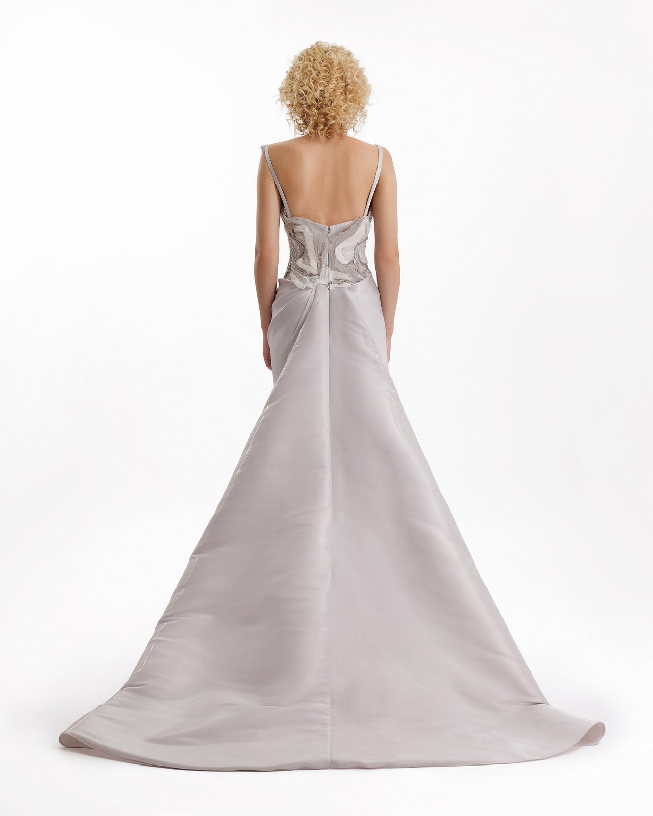 Woman wearing a silver evening gown with a white background