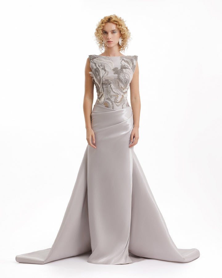 Woman wearing a silver evening gown with floral lace top on a white background