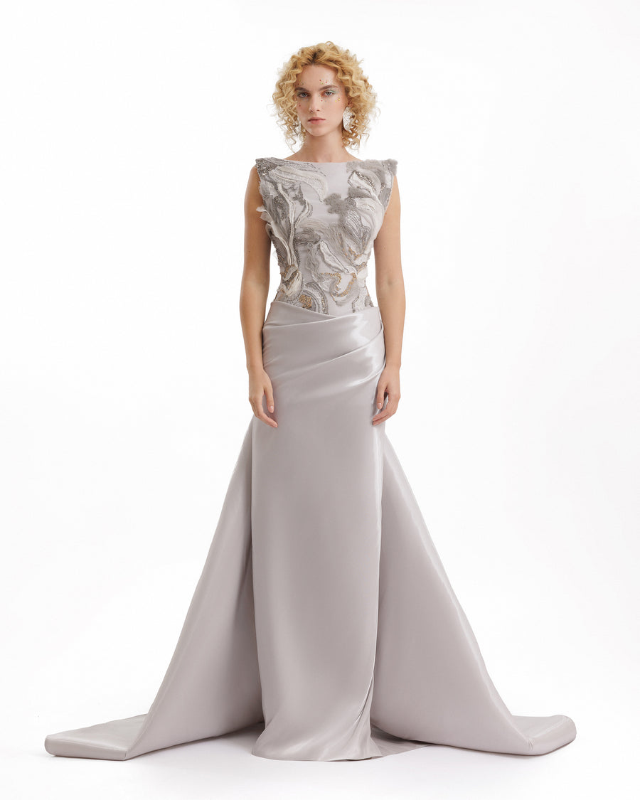 Woman wearing a silver evening gown with floral lace top on a white background