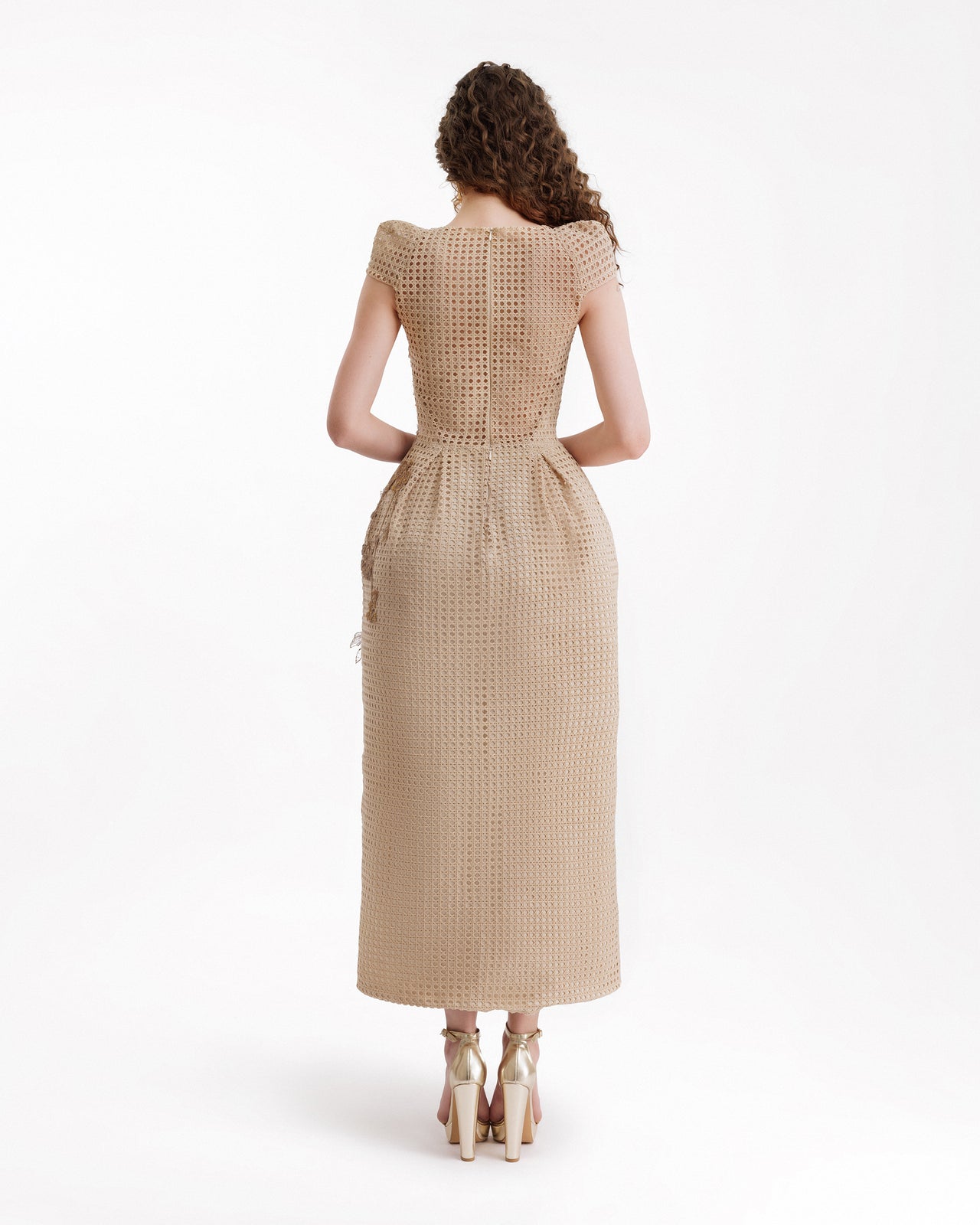 Woman wearing a beige dress with a textured pattern on a white background
