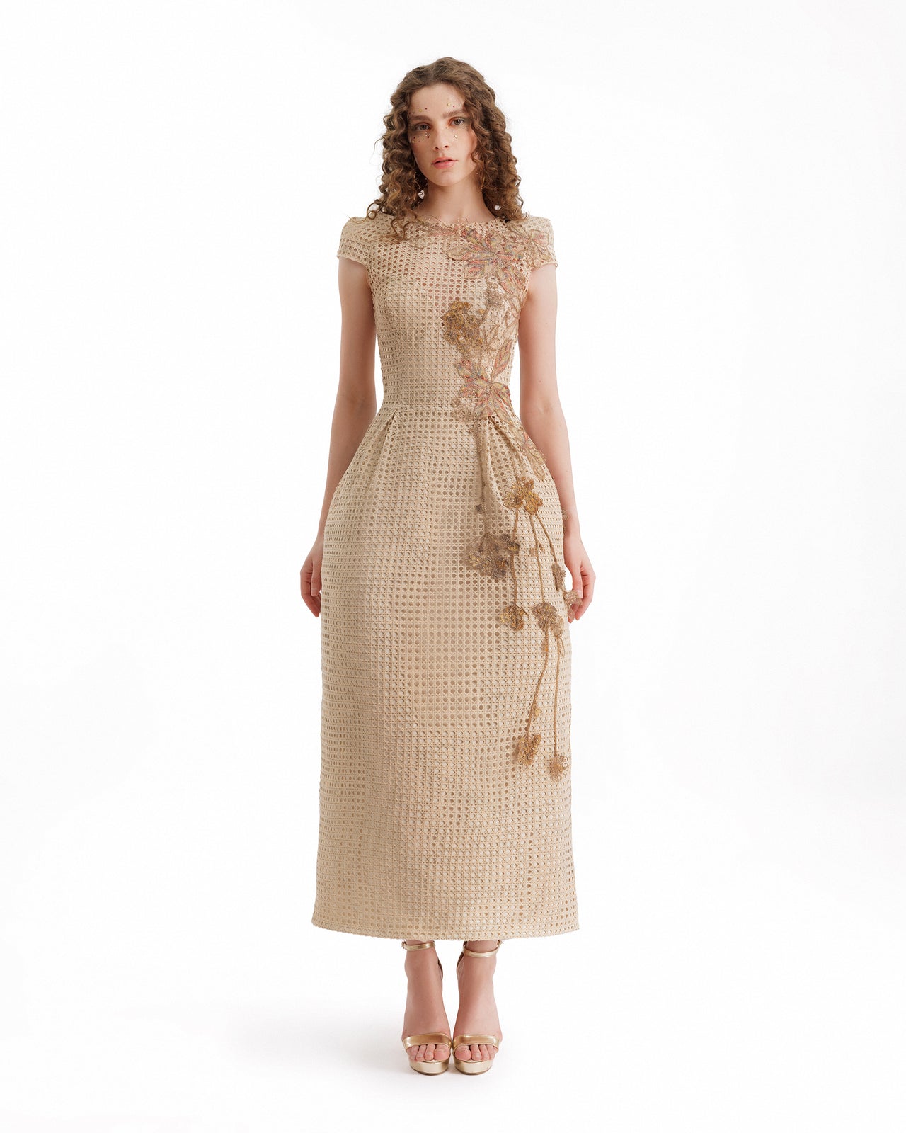 Woman wearing a beige dress with floral details on a white background