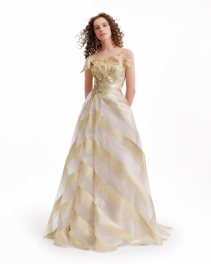 Woman wearing a gold and white striped evening gown on a white background