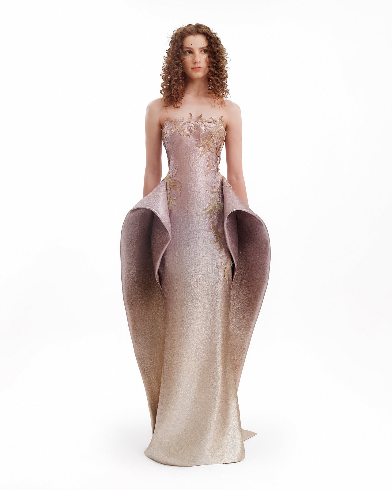 Woman wearing a strapless evening gown with floral details on a white background