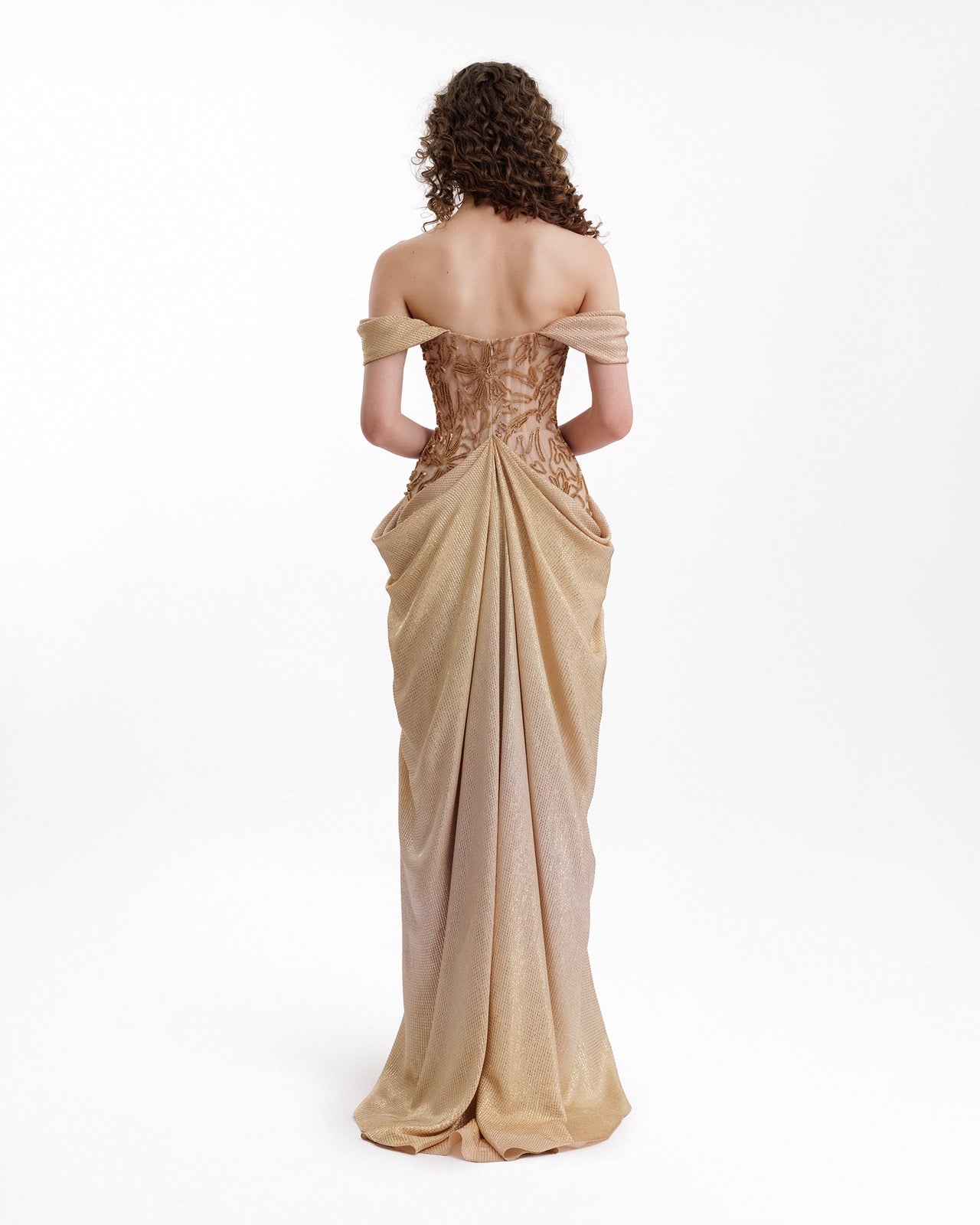 Woman wearing a beige off-shoulder evening gown on a white background