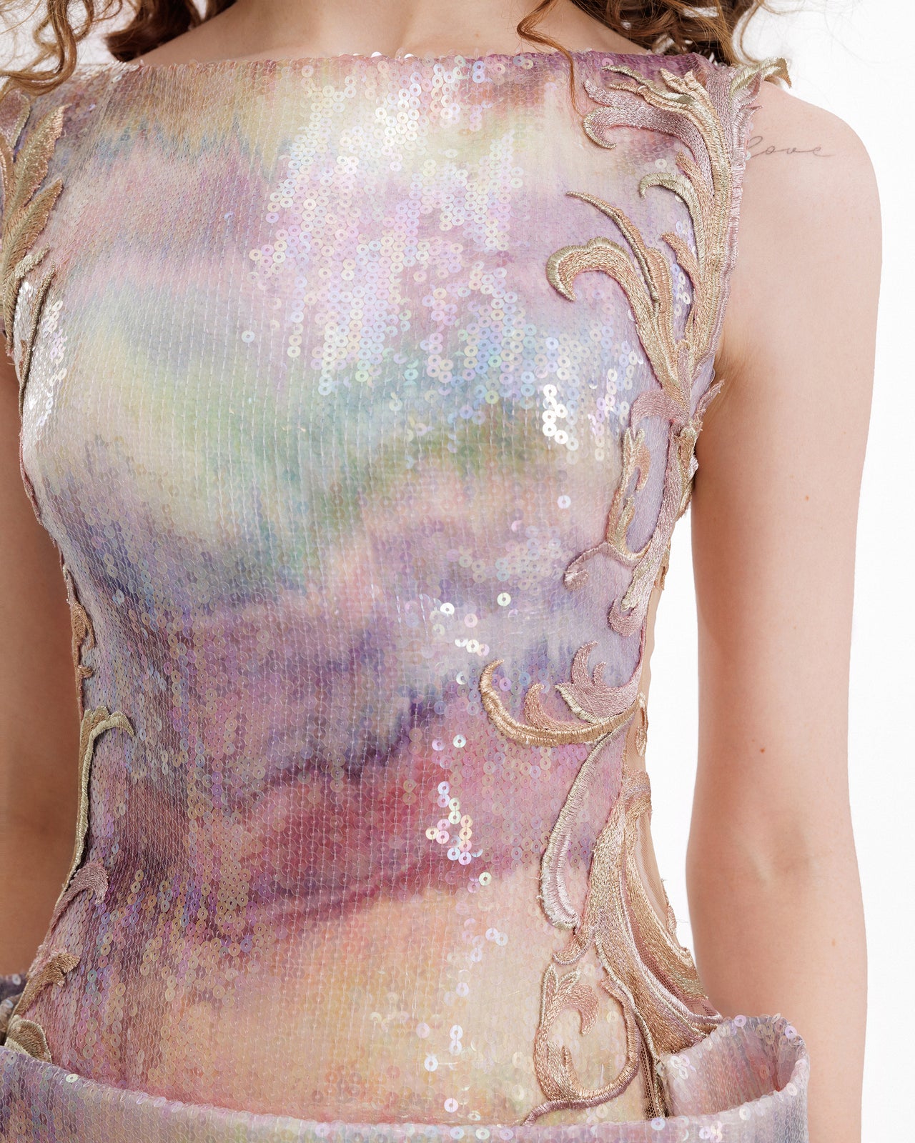 Close-up of a sequined dress with intricate designs and pastel colors.
