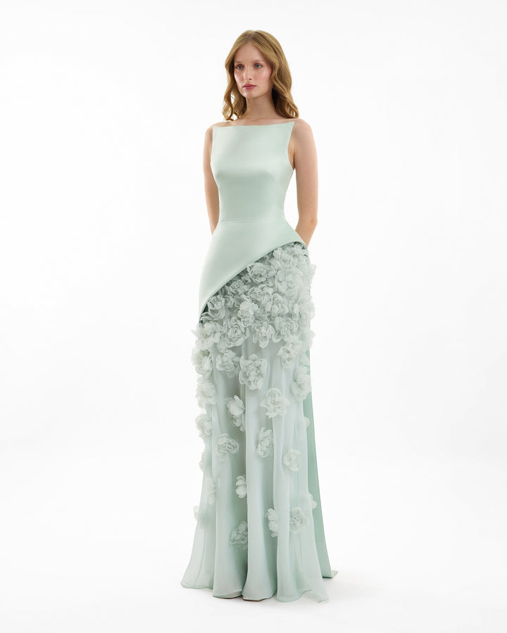 Woman wearing a light green evening gown with floral details on a white background