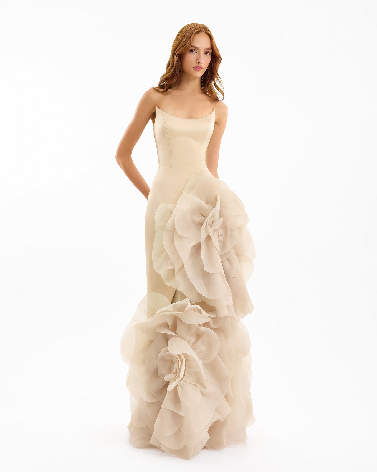 Woman wearing a beige strapless gown with floral details on a white background