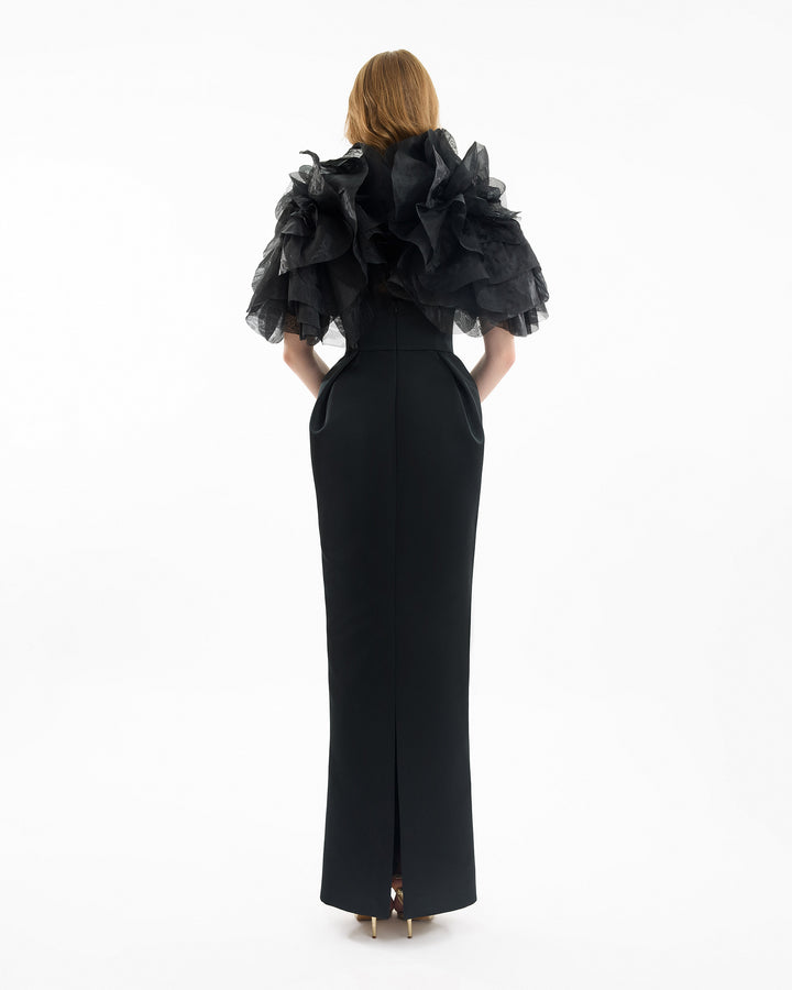Black evening gown with ruffled cape on a white background