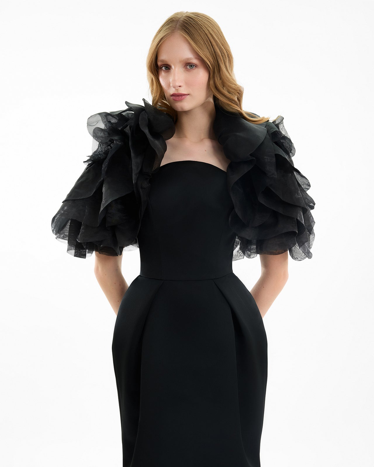 Woman wearing a black dress with ruffled sleeves on a white background